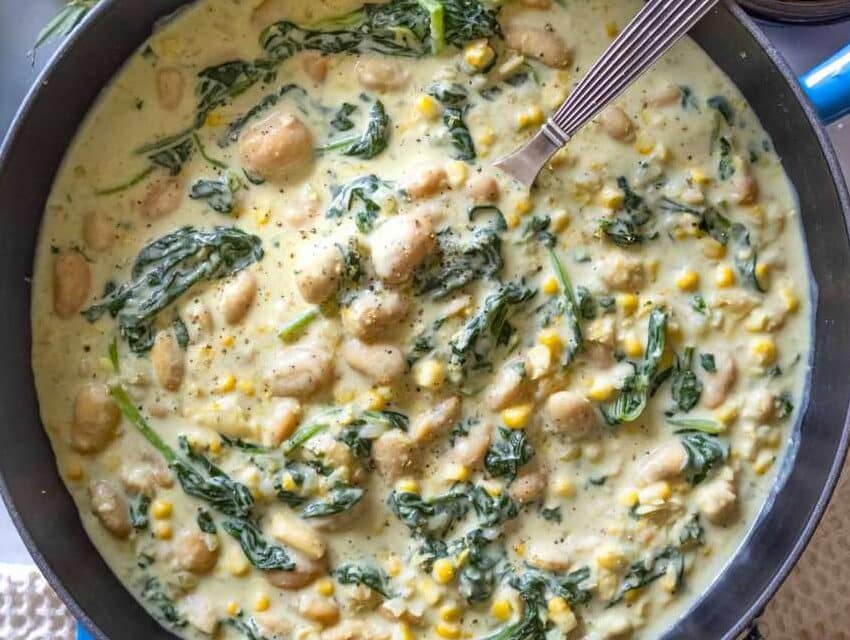 Creamy butter bean in Florentine sauce served in a blue skillet with bread.