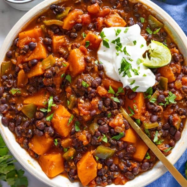 Easy black bean chili with sweet potato served in a white bowl with Greek yogurt and lime.