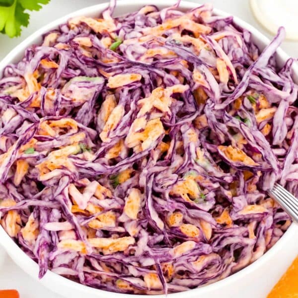 Fresh and creamy Greek Yogurt Cabbage Slaw served in a white bowl on a rustic table.