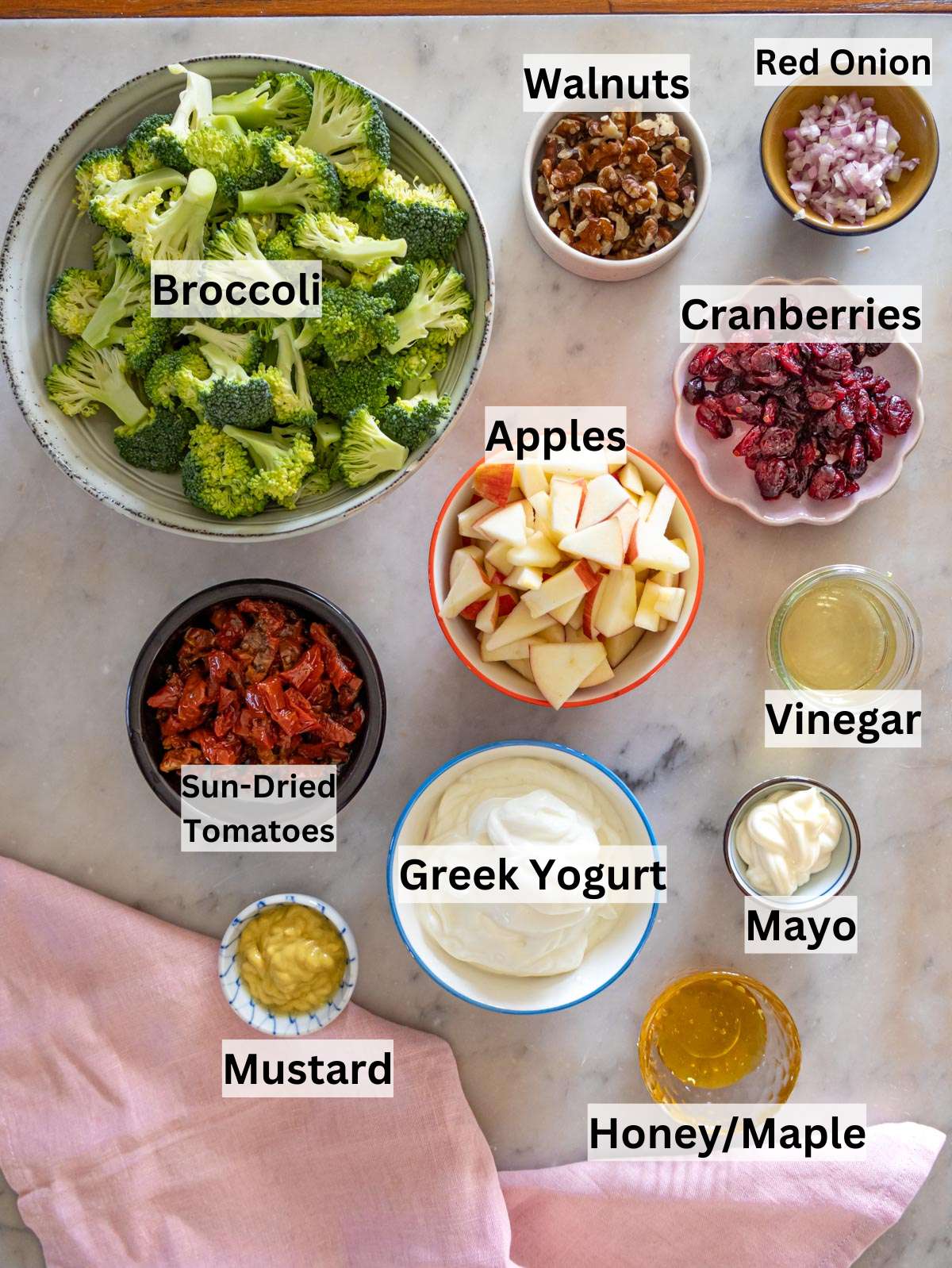 Fresh broccoli cranberries apples walnuts and Greek yogurt on a wooden table ready to mix.