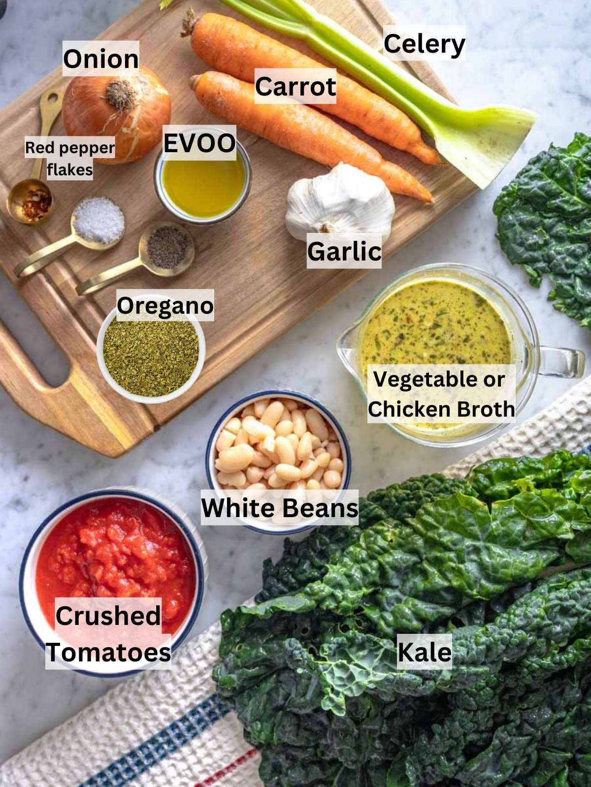Fresh ingredients for Mediterranean kale soup with kale, white beans, and tomatoes on a table.