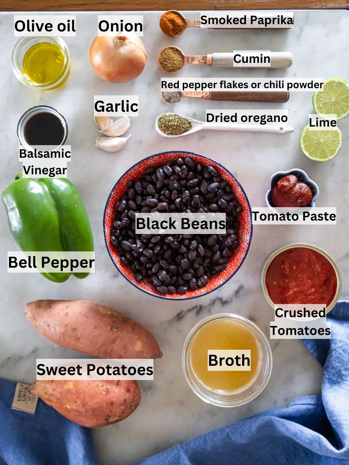 Fresh ingredients for black bean chili including sweet potatoes, beans, tomatoes, and spices.