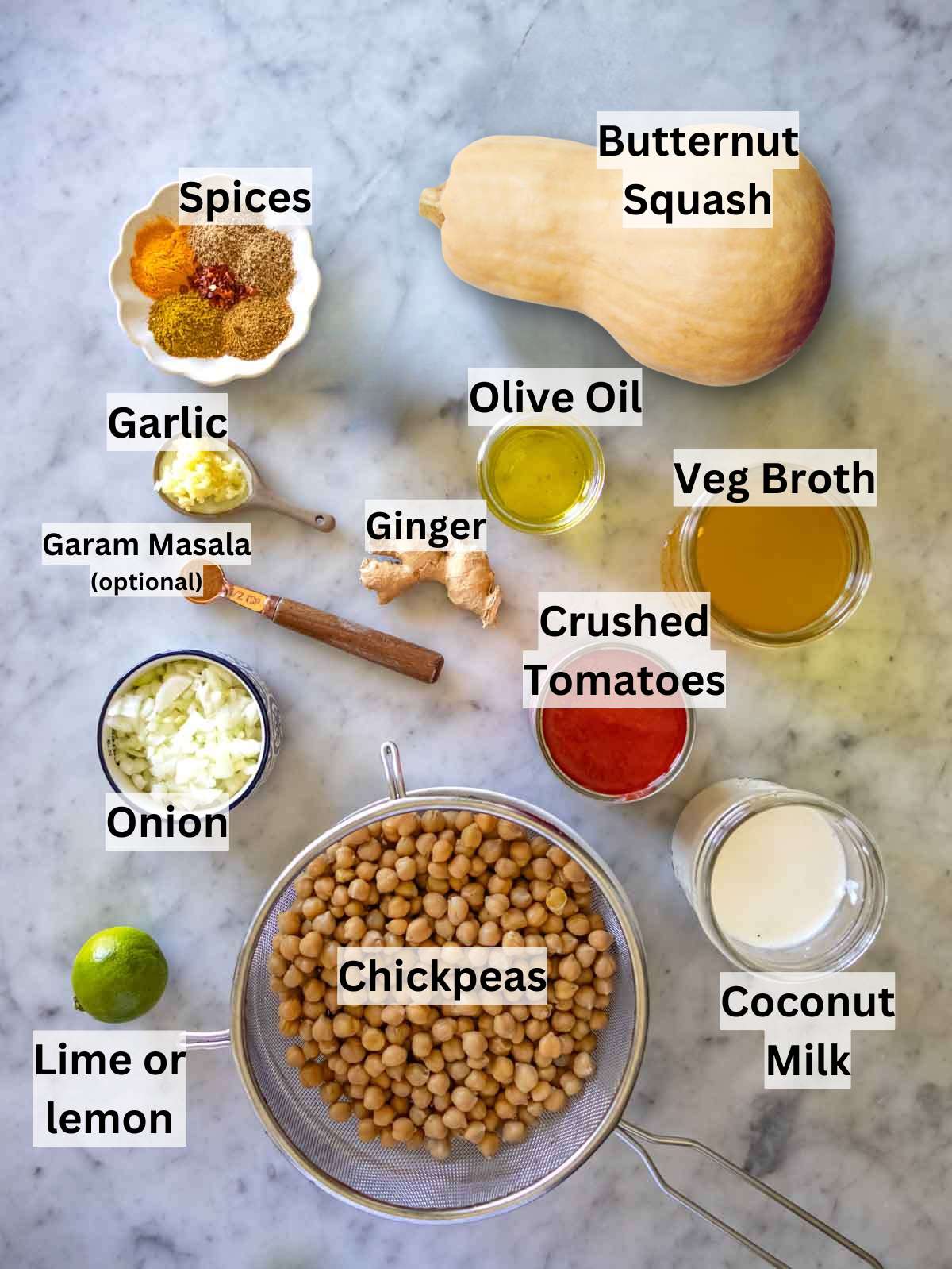 Fresh ingredients for butternut squash chickpea curry arranged neatly on a marble kitchen counter.
