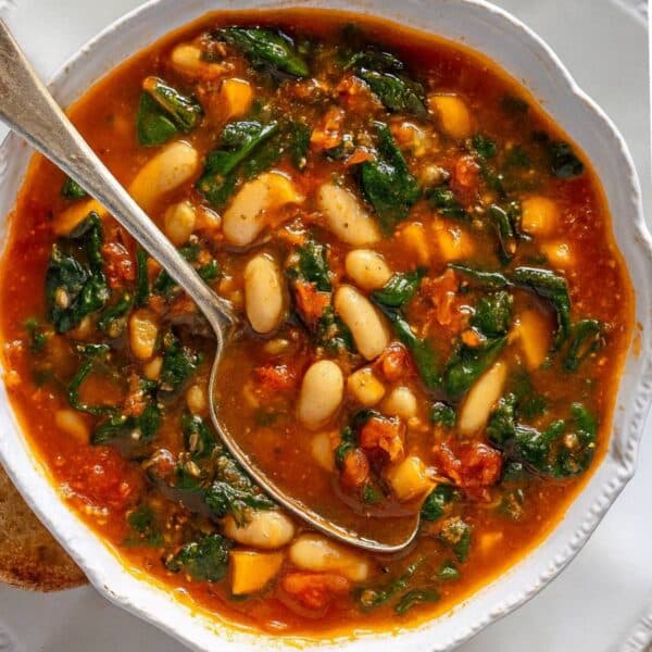 Hearty Mediterranean kale soup in a rustic bowl with bread and olive oil drizzle.