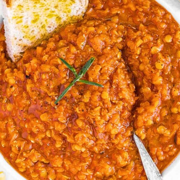 Hearty quick lentil soup with red lentils turmeric and herbs served in a bowl on a rustic wooden table.