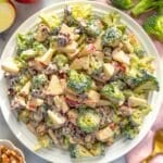 Holiday table with creamy cranberry broccoli salad served on a white platter with spoon.