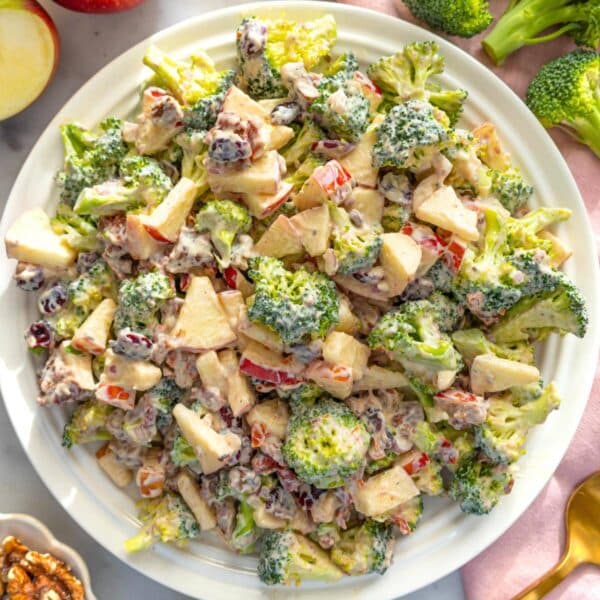 Holiday table with creamy cranberry broccoli salad served on a white platter with spoon.