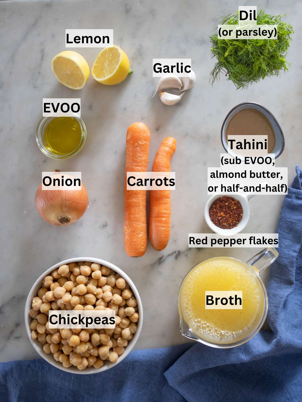 Ingredients for Greek chickpea soup arranged neatly on table with olive oil lemon and chickpeas.
