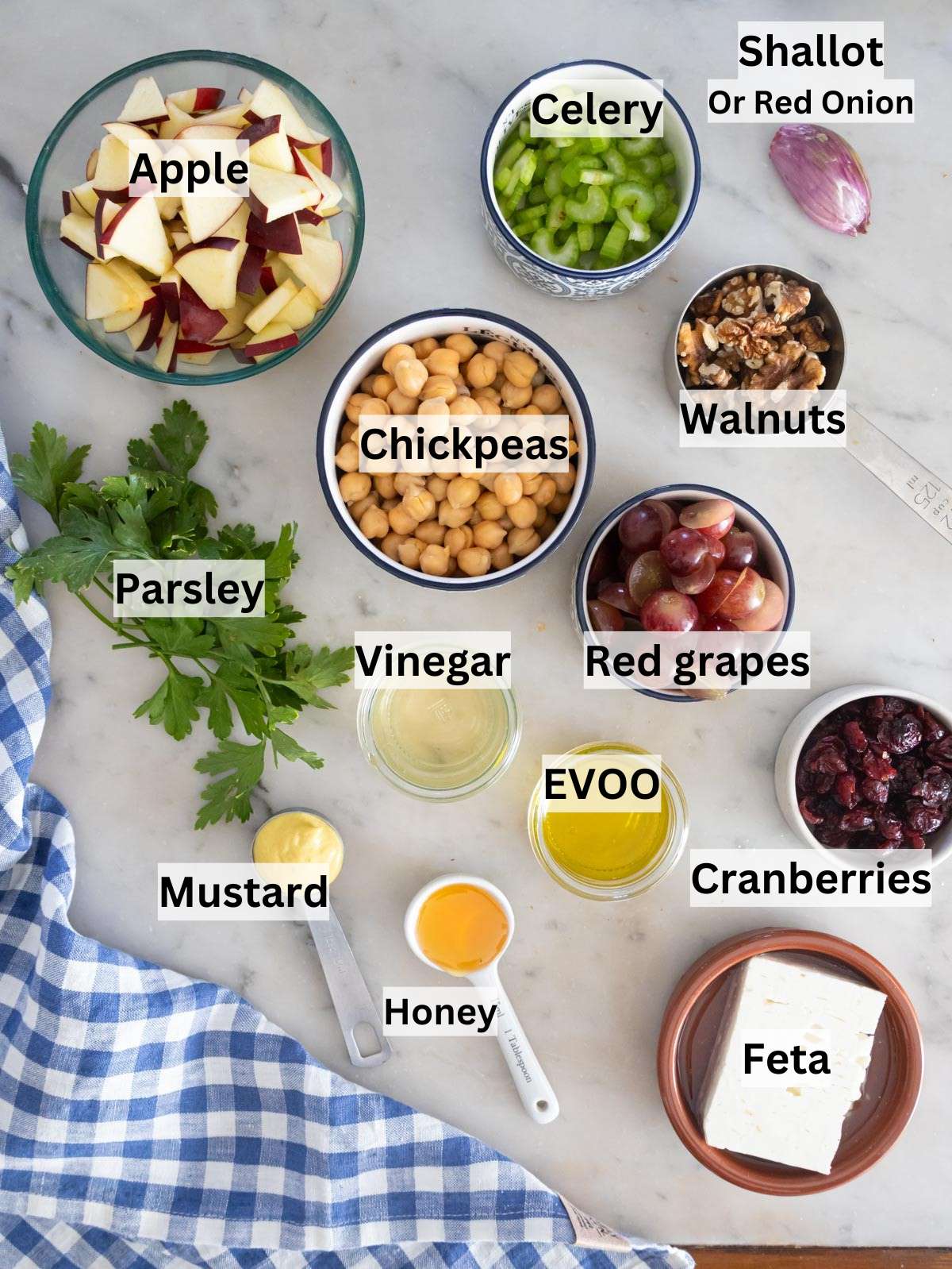 Ingredients for chickpea cranberry salad including chickpeas grapes apple celery feta and honey.