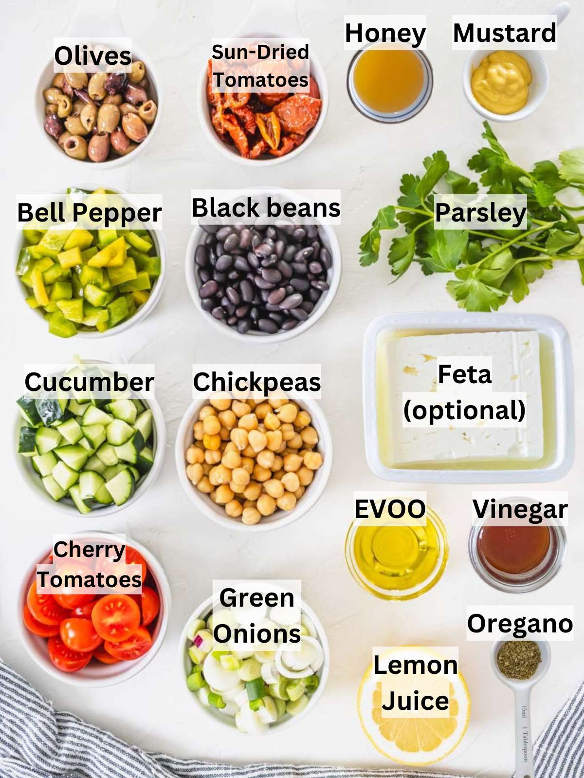 Mediterranean bean salad ingredients arranged on a table with beans, vegetables, and olive oil.