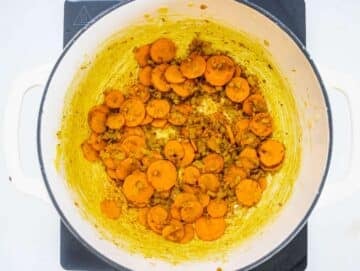 Step 1 Chopped onions and carrots sautéing with turmeric in olive oil in a pot.