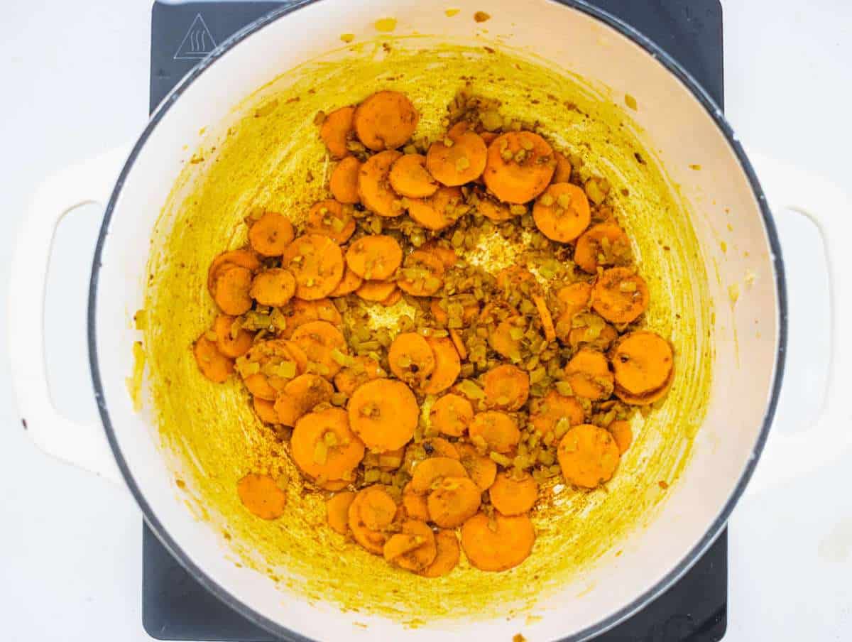 Step 1 Chopped onions and carrots sautéing with turmeric in olive oil in a pot.