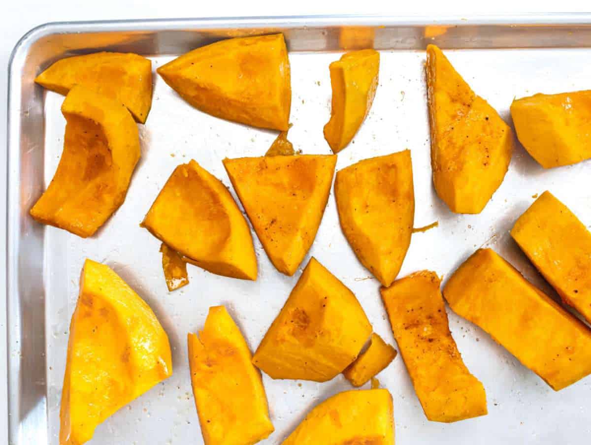 Step 1 Raw pumpkin chunks spread on a baking sheet ready to roast for soup.
