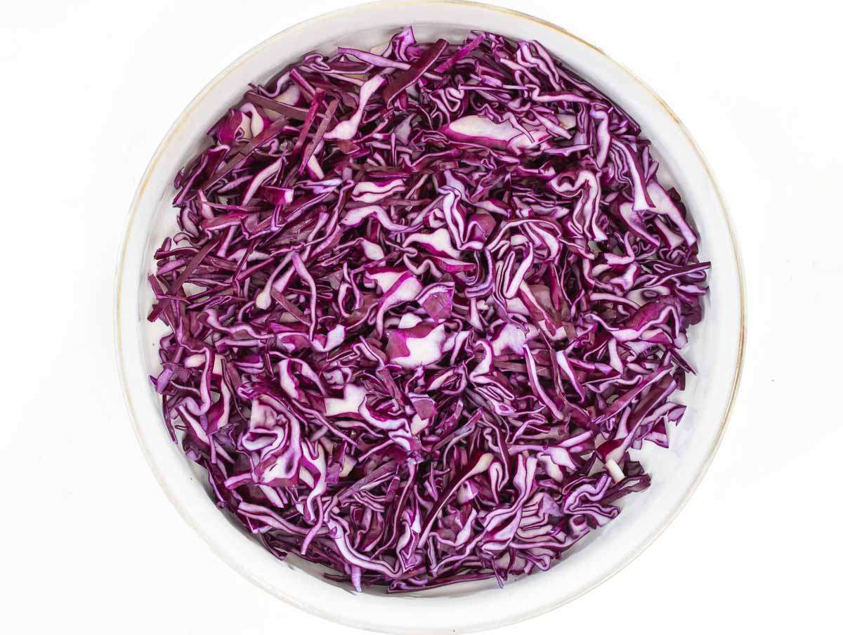 Step 1 Thinly sliced red cabbage in a bowl ready for Greek Yogurt Cabbage Slaw.