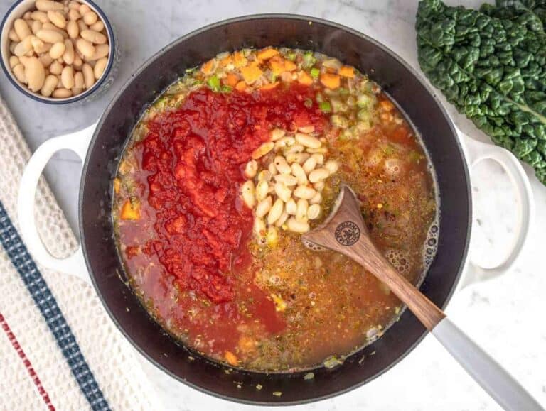Step 2 Adding crushed tomatoes, beans, and broth into the pot for healthy Mediterranean kale soup.