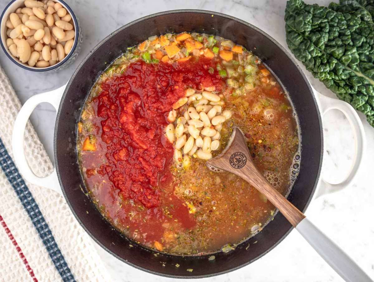 Step 2 Adding crushed tomatoes, beans, and broth into the pot for healthy Mediterranean kale soup.