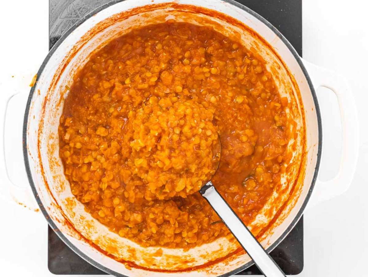Step 2 Adding red lentils, tomatoes, and broth to the pot for simmering.