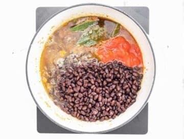 Step 2 Black beans tomatoes and broth simmering together in a pot.