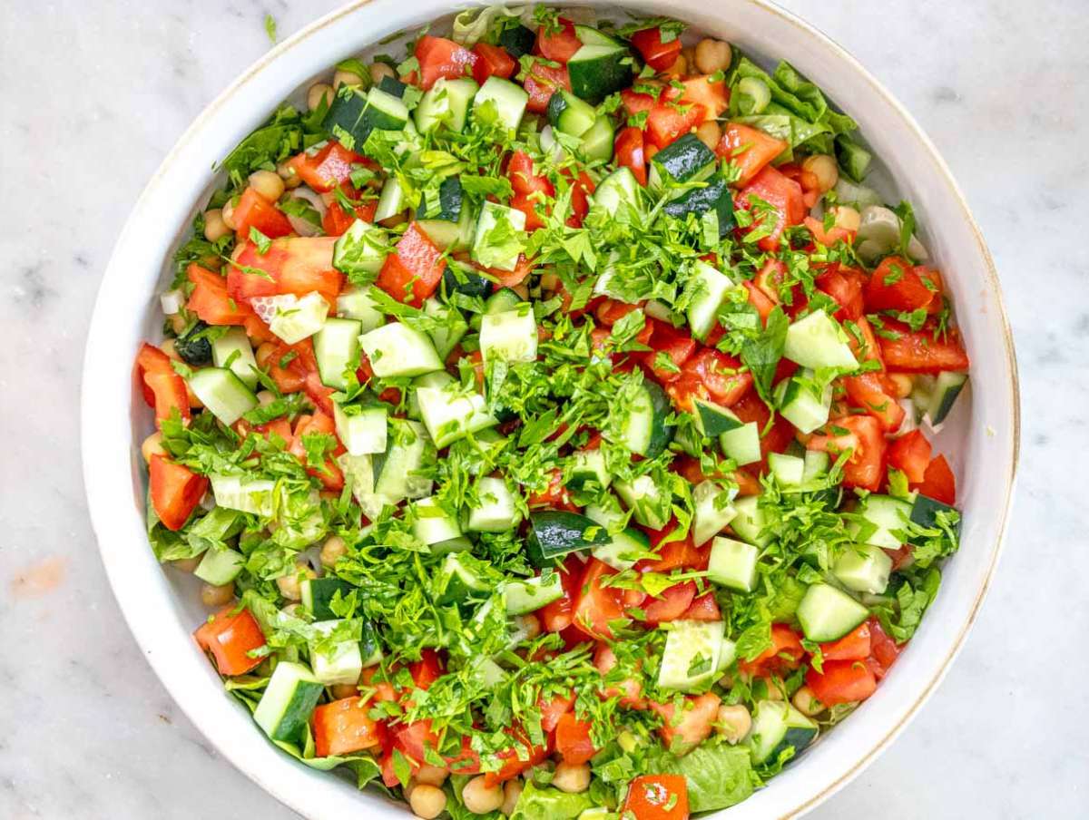 Step 2 Chopping lettuce cucumber tomato parsley and green onions for fresh salad base.