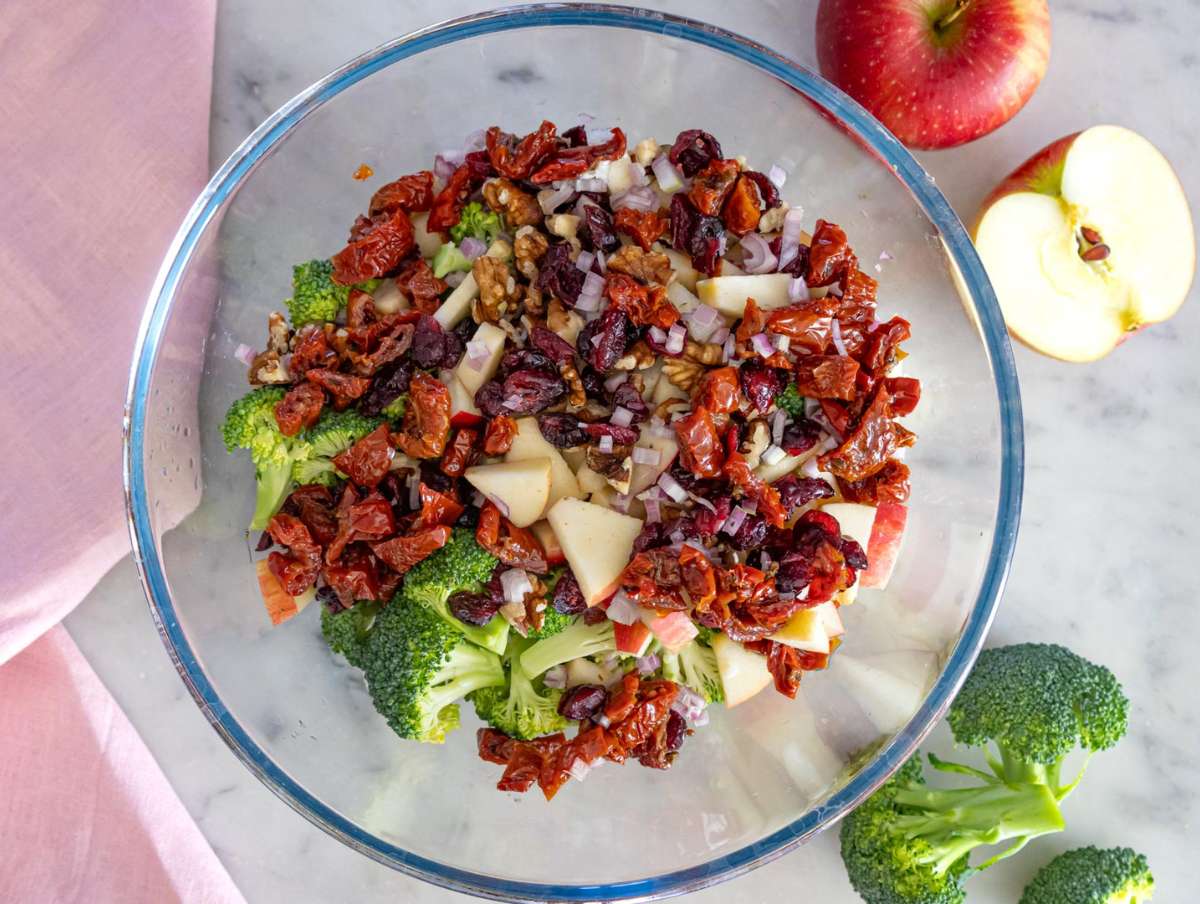 Step 2 Mixing cranberries apples walnuts and sun-dried tomatoes into chopped broccoli.