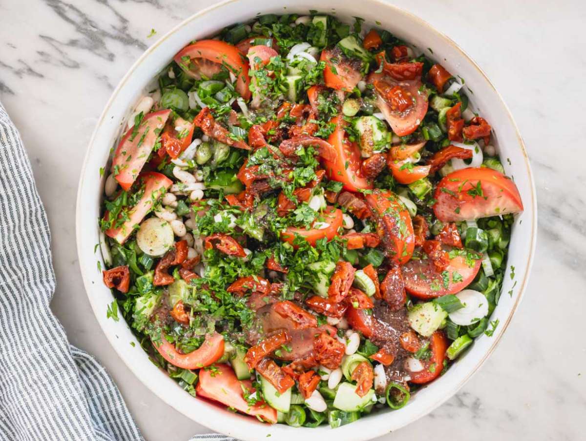Step 3 Chopped tomatoes cucumber and herbs in a large bowl for white bean salad.