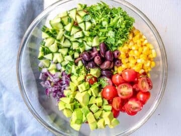 Step 3 Chopped tomatoes cucumber olives and parsley in a bowl for the Mediterranean quinoa salad.
