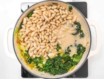 Step 3 Stirring beans and vegetables together simmering Mediterranean cabbage bean stew.