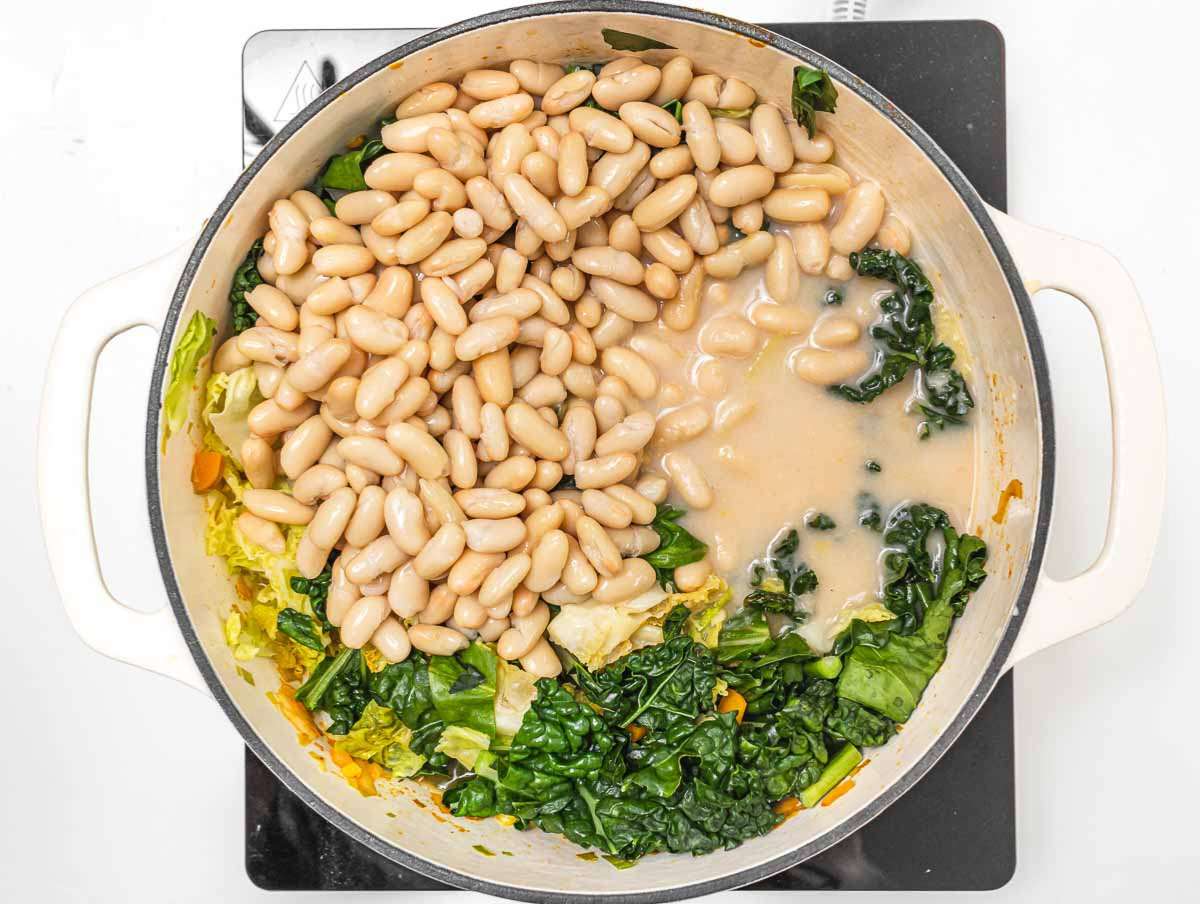 Step 3 Stirring beans and vegetables together simmering Mediterranean cabbage bean stew.