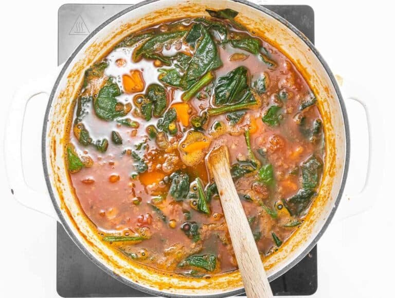 Step 3 Stirring fresh spinach into the soup until wilted.