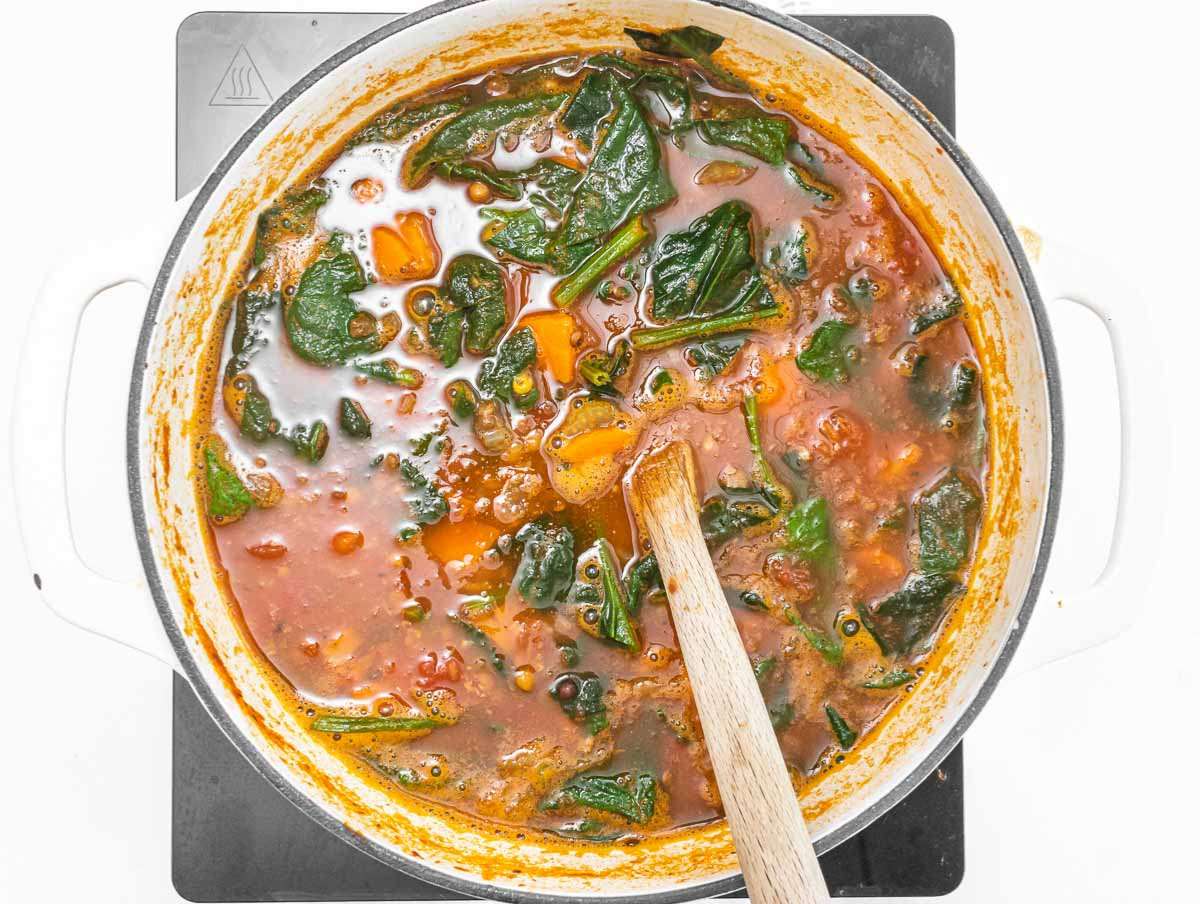 Step 3 Stirring fresh spinach into the soup until wilted.