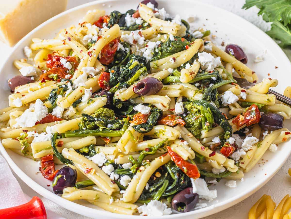 Step 4 Greek inspired mediterranean pasta served on a plate with crumbled feta.