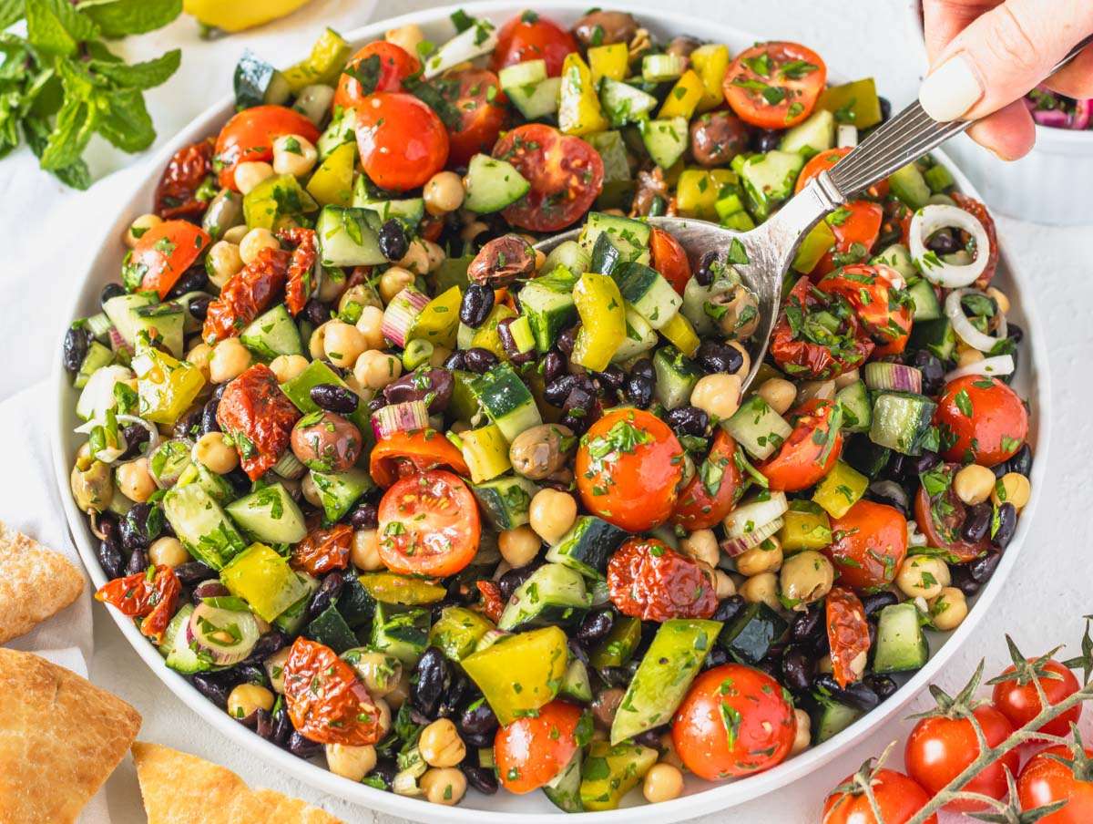 Step 4 Serving Mediterranean bean salad on a platter and Louise scooping it up with a spoon.