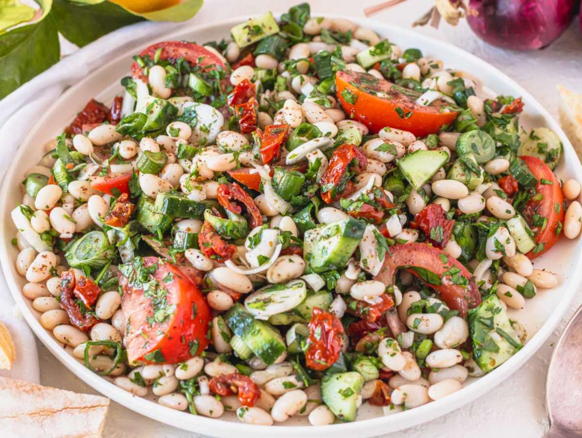 Step 4 Tossing white beans and veggies together until coated and ready to serve.