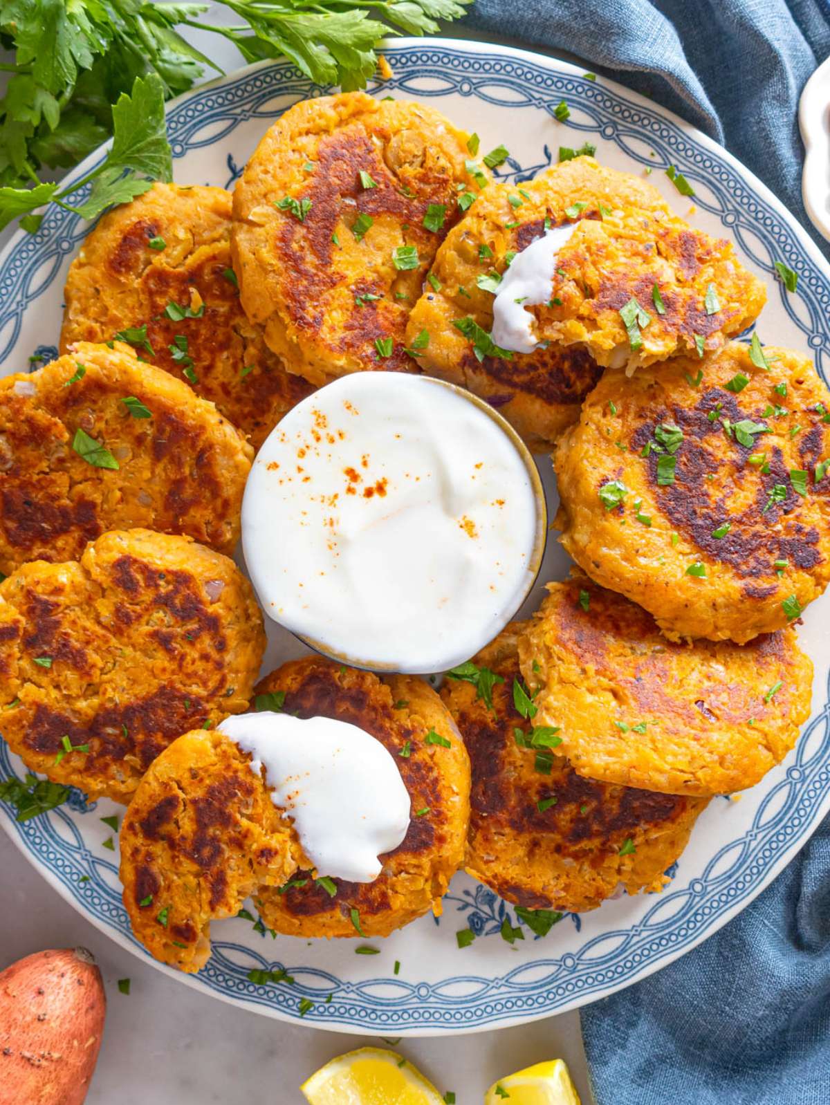 Top down finished dish – Plate of chickpea sweet potato patties served with yogurt and fresh salad.