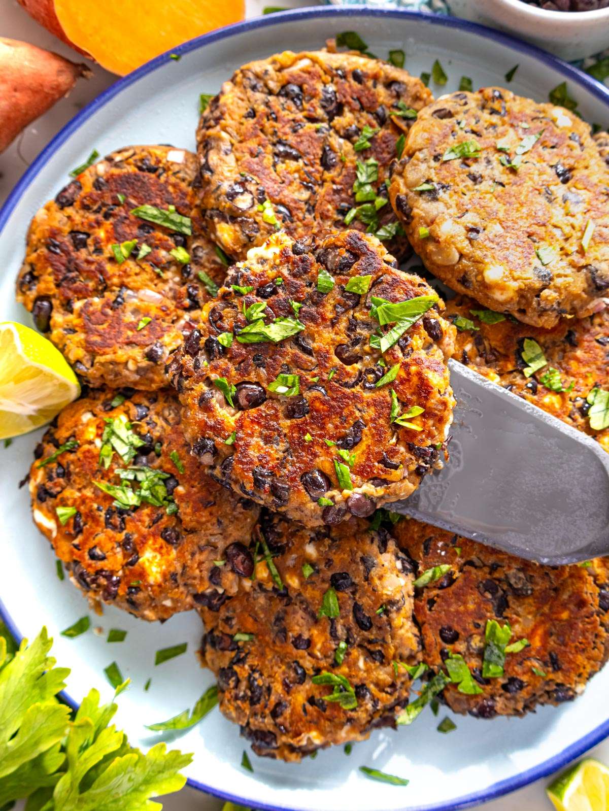 Top down view of black bean patties topped with fresh herbs on a rustic table.