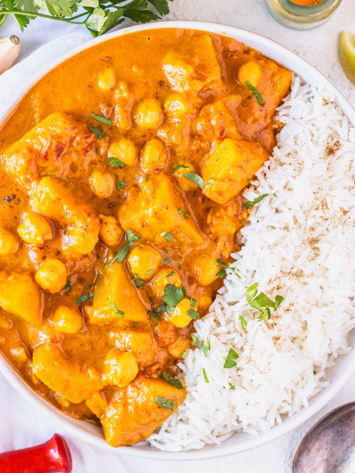 Top down view of butternut squash chickpea curry and basmati rice in a white bowl.