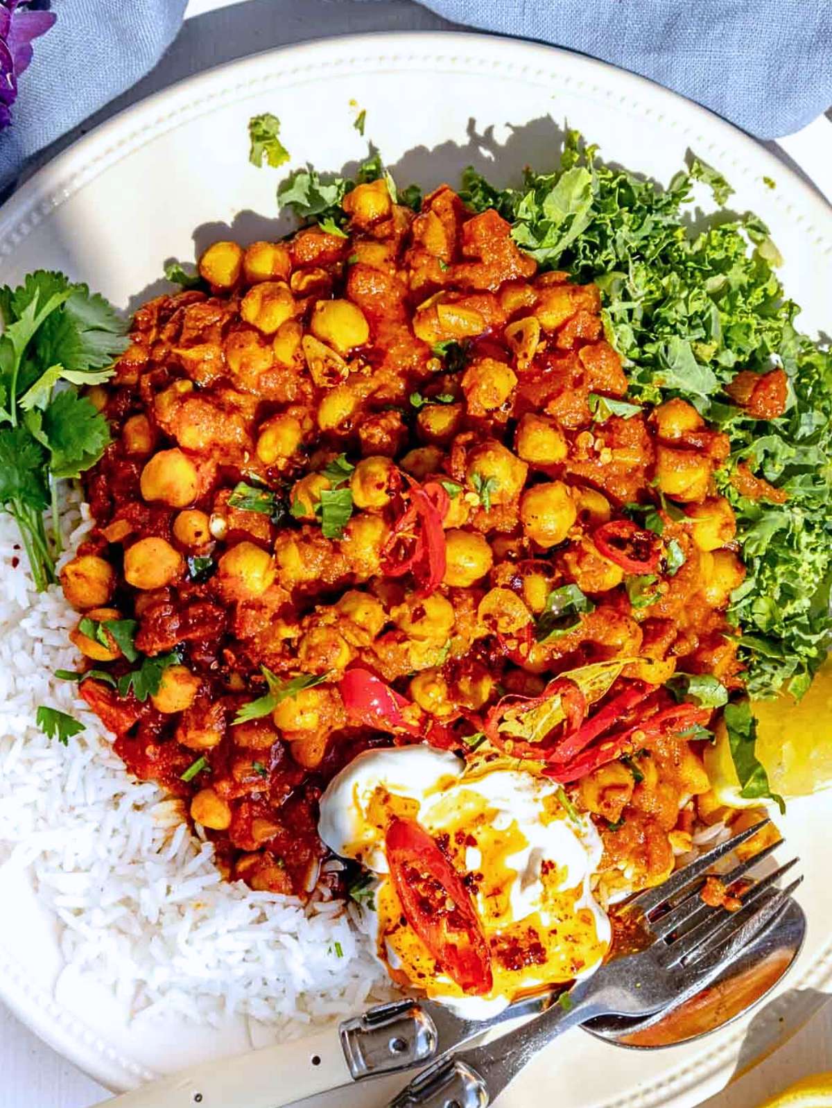 Top down view of chickpea masala with naan bread and yogurt topping.