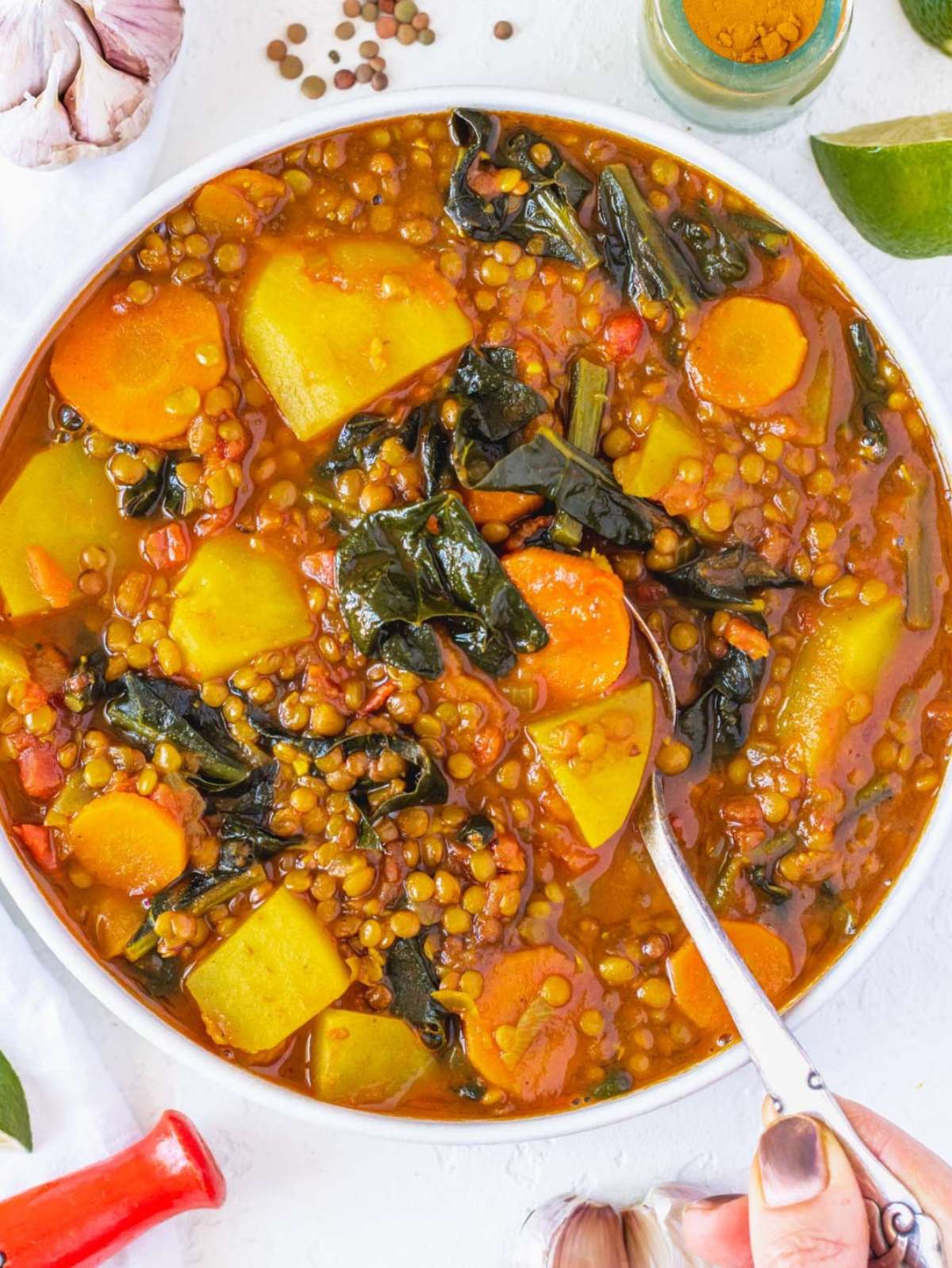 Top down view of hearty turmeric lentil soup served with bread and lemon slices.