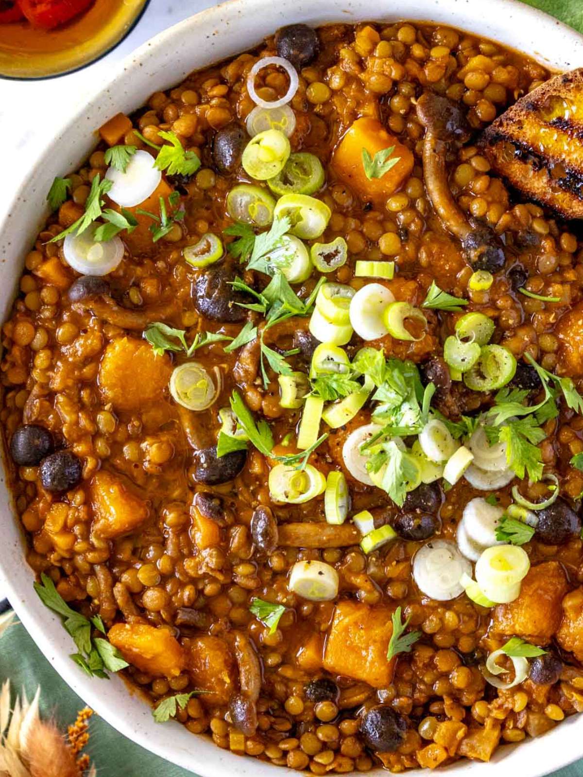 Top down view of lentil pumpkin stew showing colorful vegetables and creamy texture.