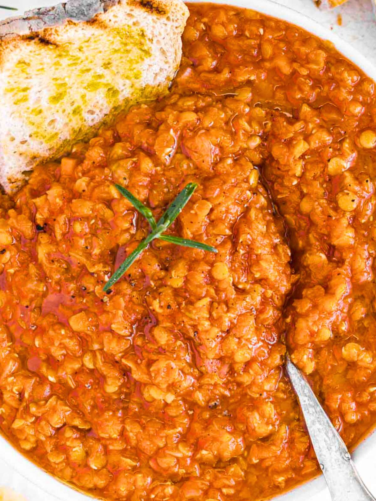 Top down view of quick lentil soup with crusty bread and fresh rosemary.