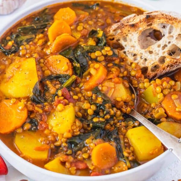 Warm turmeric lentil soup with spinach and potatoes in a rustic Mediterranean setting.