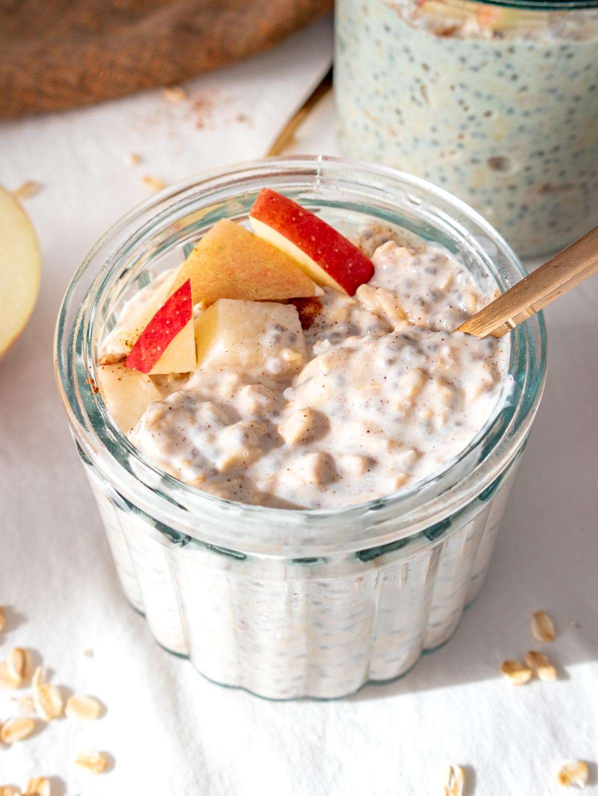 Apple cinnamon overnight oats in a single portion glass jar topped with apple and cinnamon.