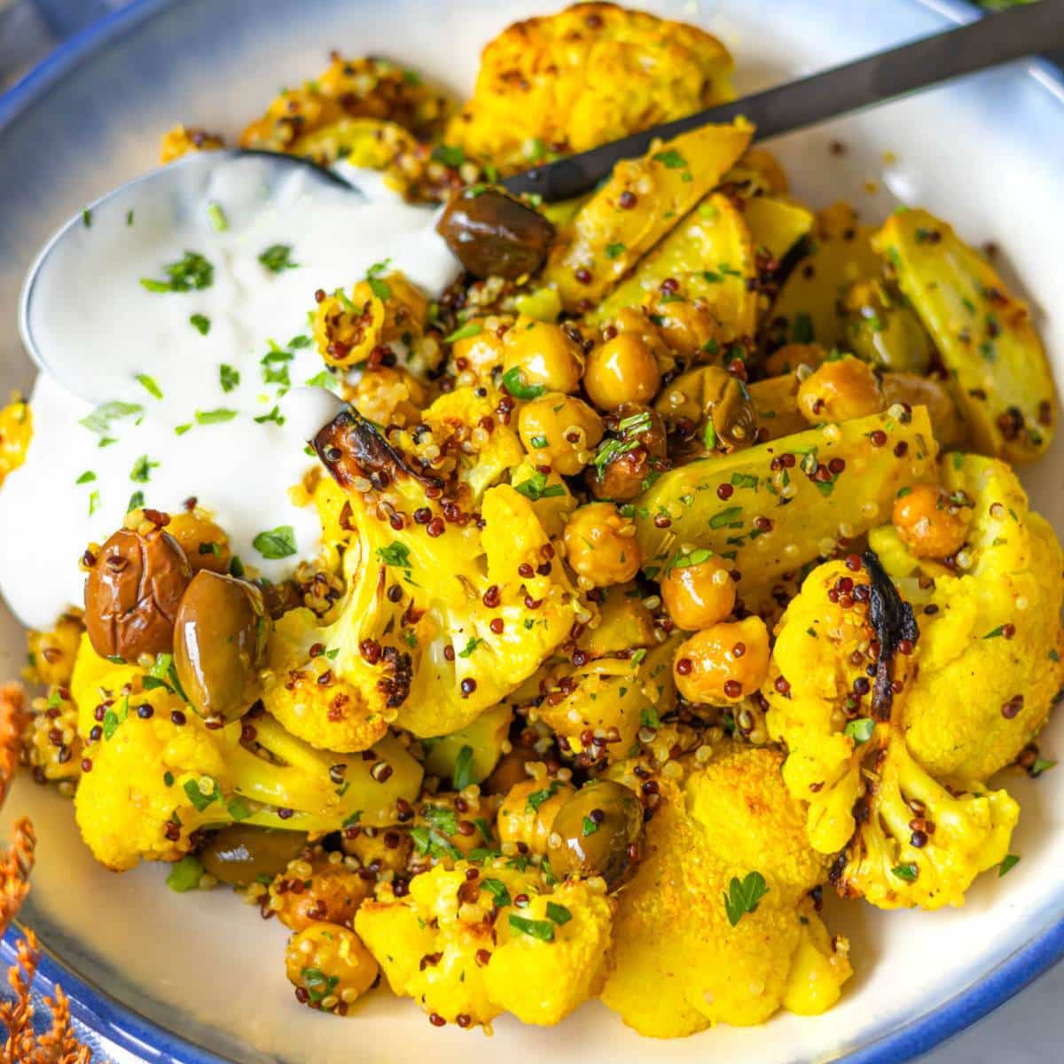 Bowl of vibrant turmeric cauliflower and chickpea sheet pan dinner with fresh herbs.