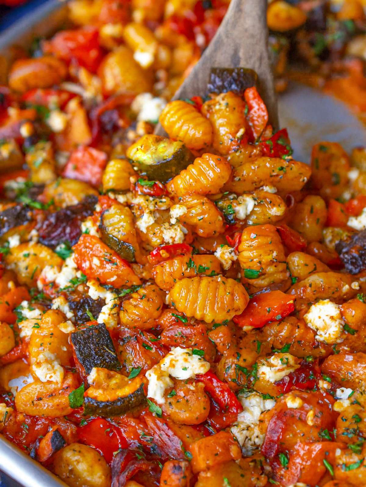 Close up finished dish Greek sheet pan gnocchi with roasted vegetables feta and herbs.