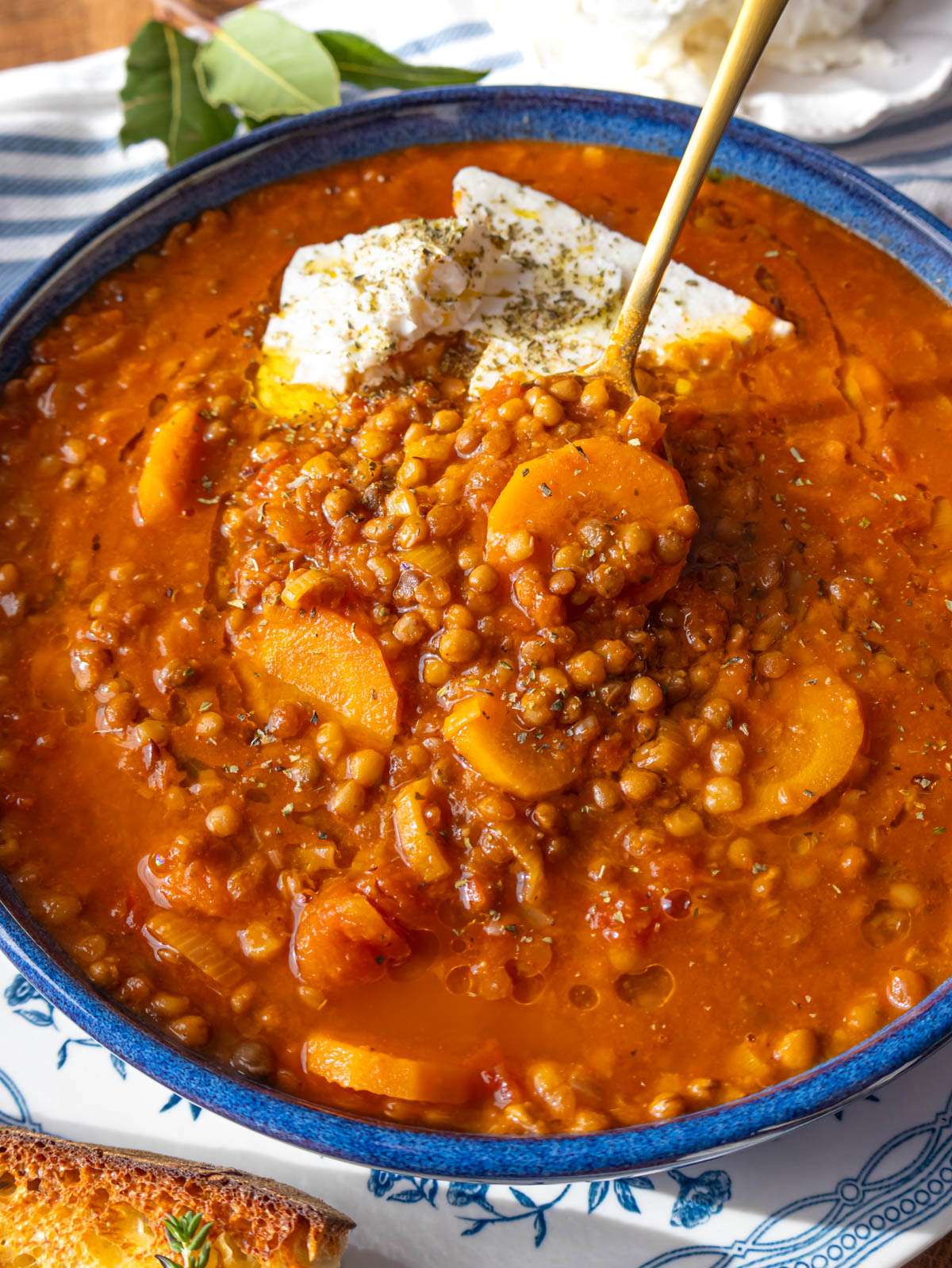 Close up of Greek lentil soup with olive oil drizzle and feta on top.