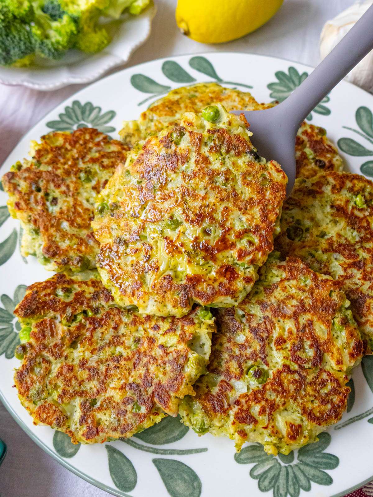 Close-up of crispy broccoli fritters with golden edges and lemon on the side.