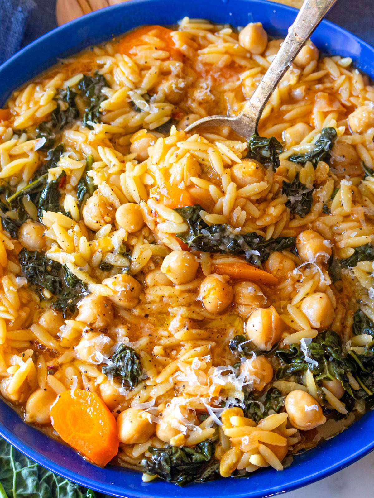 Cozy chickpea orzo recipe served in a bowl with kale and carrots.