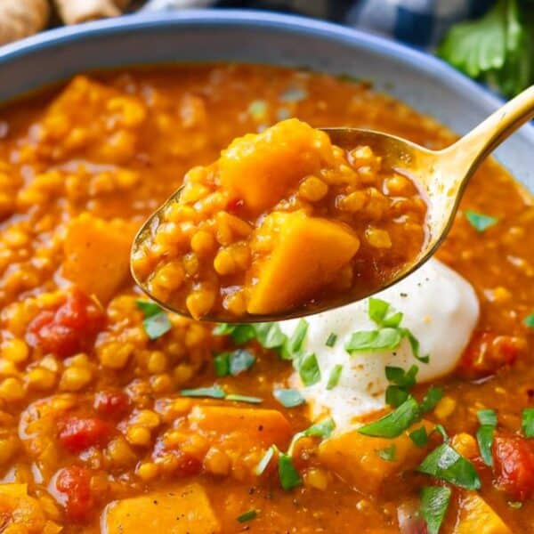 Feature image showing a curried red lentil soup with yogurt swirl lemon and fresh herbs.