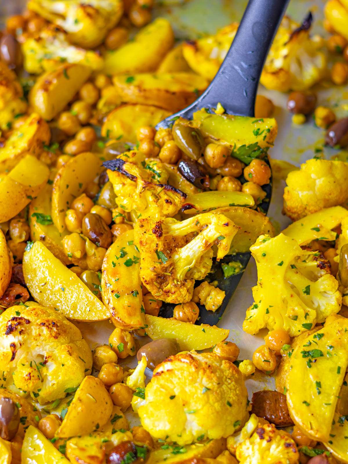 Finished dish close up golden turmeric cauliflower and chickpeas with lemon and parsley.