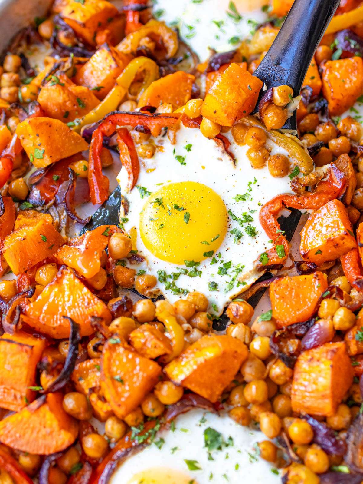 Finished dish close up showing tender roasted veggies and baked eggs Mediterranean style.
